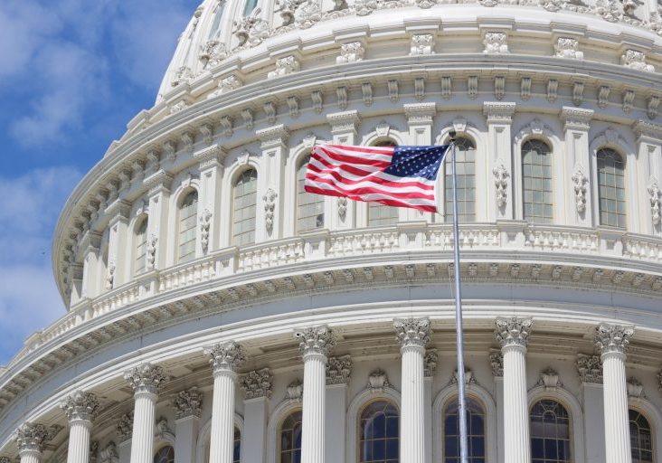 A flag flies in front of the capitol building.